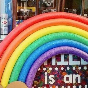 there is a fake rainbow in front of a store window with the words hello is an awesome day on it