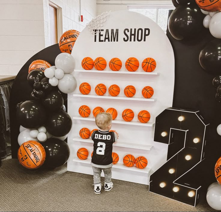 a little boy standing in front of a basketball display