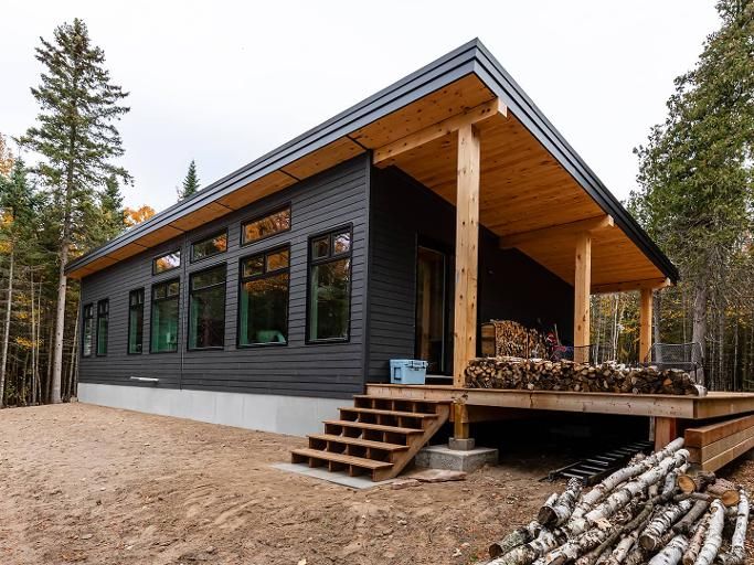 a small cabin in the woods with stairs leading up to it's second floor