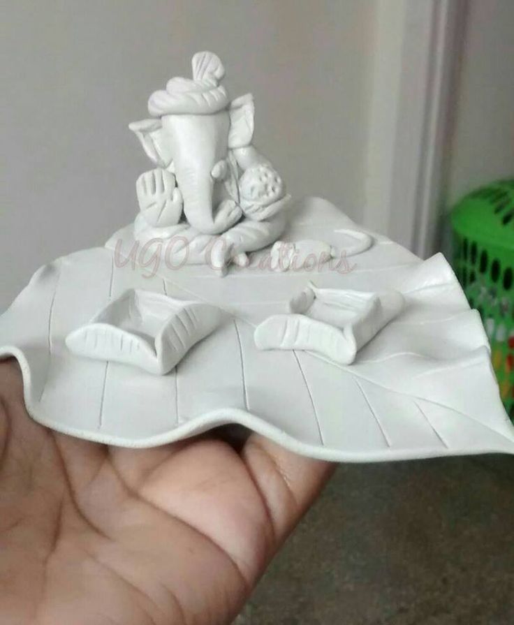 a hand is holding a small model of a boat on top of a white plate