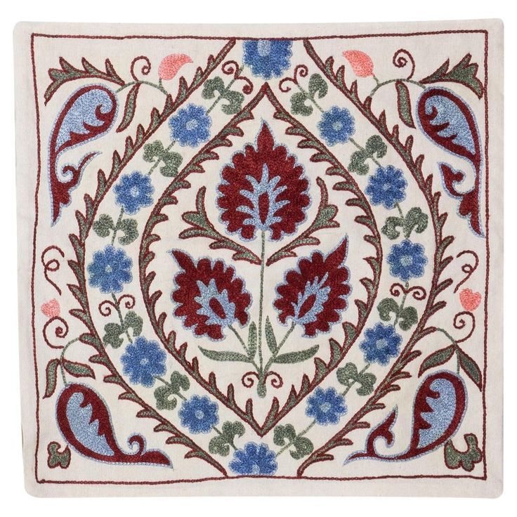 an embroidered square with blue, red and green flowers on white fabric in the center