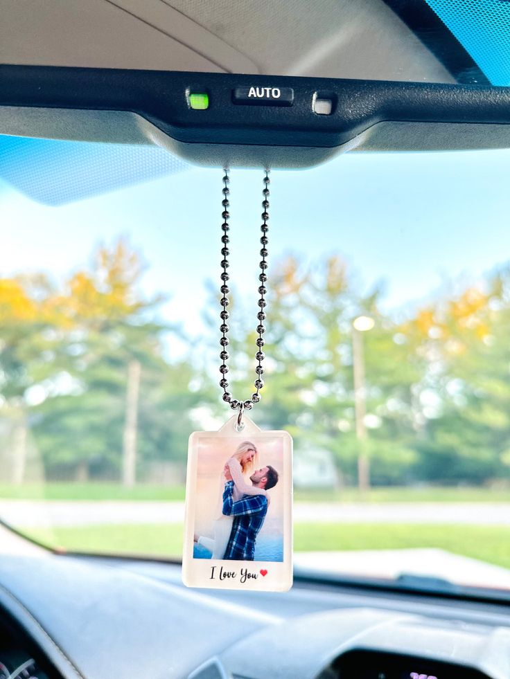 a photo hanging from the dashboard of a car with a chain attached to it that says i love you