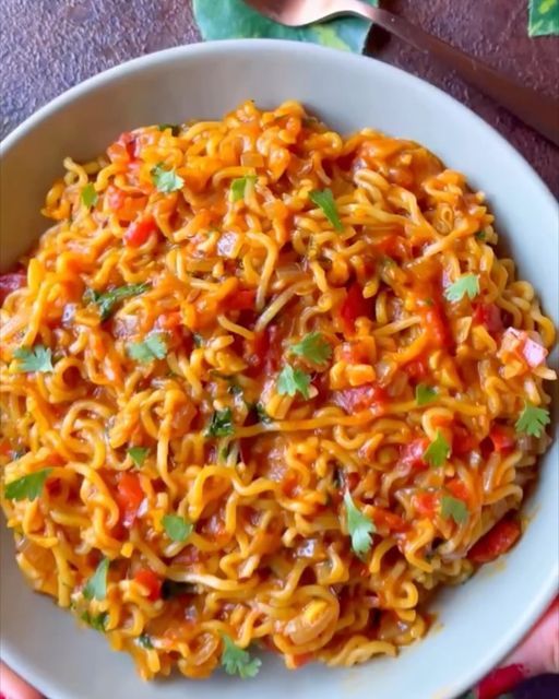 a white bowl filled with noodles and garnished with cilantro, red peppers and parsley