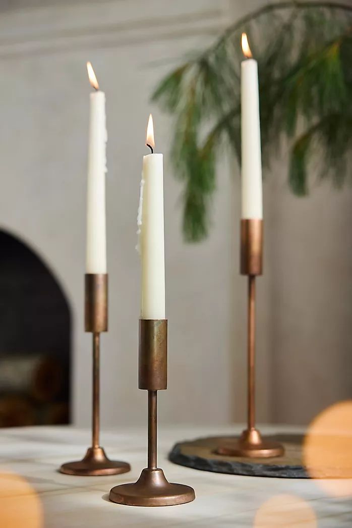 three candles sitting on top of a table next to each other in front of a fireplace