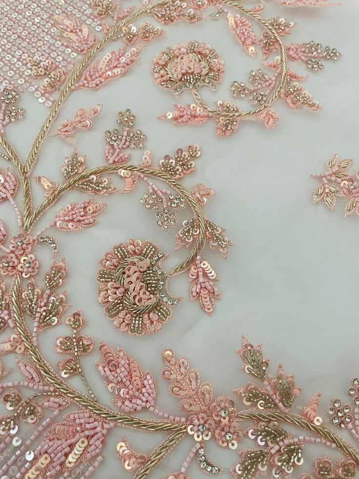 an embroidered fabric with pink flowers and leaves on it's side, is shown