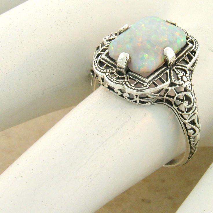 a white ring with an opal in the center and filigrees around it