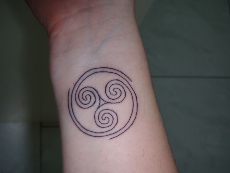 a tattoo on the wrist of a person with a small symbol in it's center