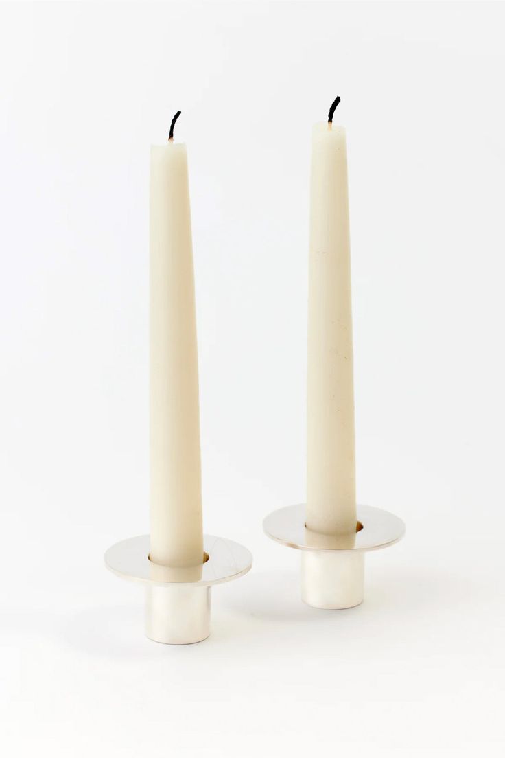 two white candles sitting on top of each other