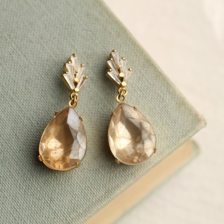 These art deco earrings feature a stylised crystal geometric design with an amazing, ivory champagne coloured glass stone.  The drop and settings are solid brass. The earrings have a post fastening with butterfly backs.  The posts are made of surgical steel. The length of these earrings is around an inch and a half (35mm) with the pearl designed to sit around an inch below the earlobe.   This piece of jewellery comes packaged in a nice recycled gift box with a handmade tag, all ready to give or Gold Art Deco Clip-on Earrings For Formal Occasions, Formal Art Deco Dangle Bridal Earrings, Formal Art Deco Bridal Dangle Earrings, Art Deco Dangle Bridal Earrings For Formal Occasions, Art Deco Crystal Drop Earrings For Wedding, Antique Gold Chandelier Earrings For Wedding, Vintage Teardrop Crystal Earrings For Formal Occasions, Vintage Crystal Teardrop Earrings For Formal Occasions, Vintage Clip-on Bridal Earrings For Wedding