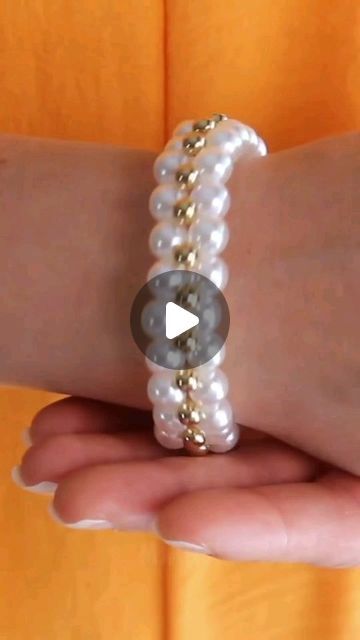 a woman's hand holding a bracelet with pearls and gold beads on the wrist