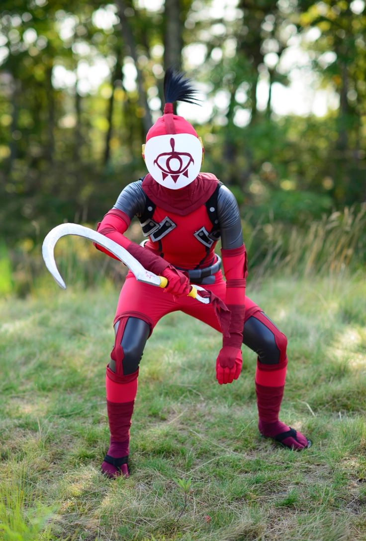 a person in a red and black costume holding a white frisbee while standing on some grass