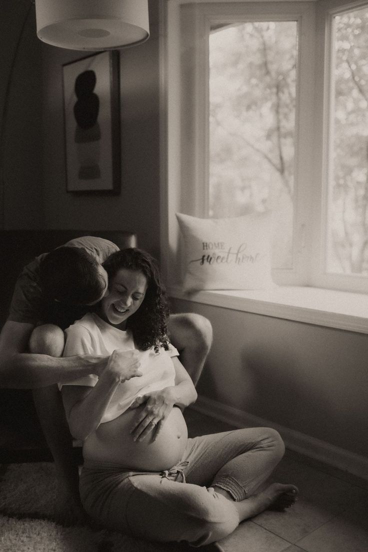 a pregnant woman sitting on the floor with her baby