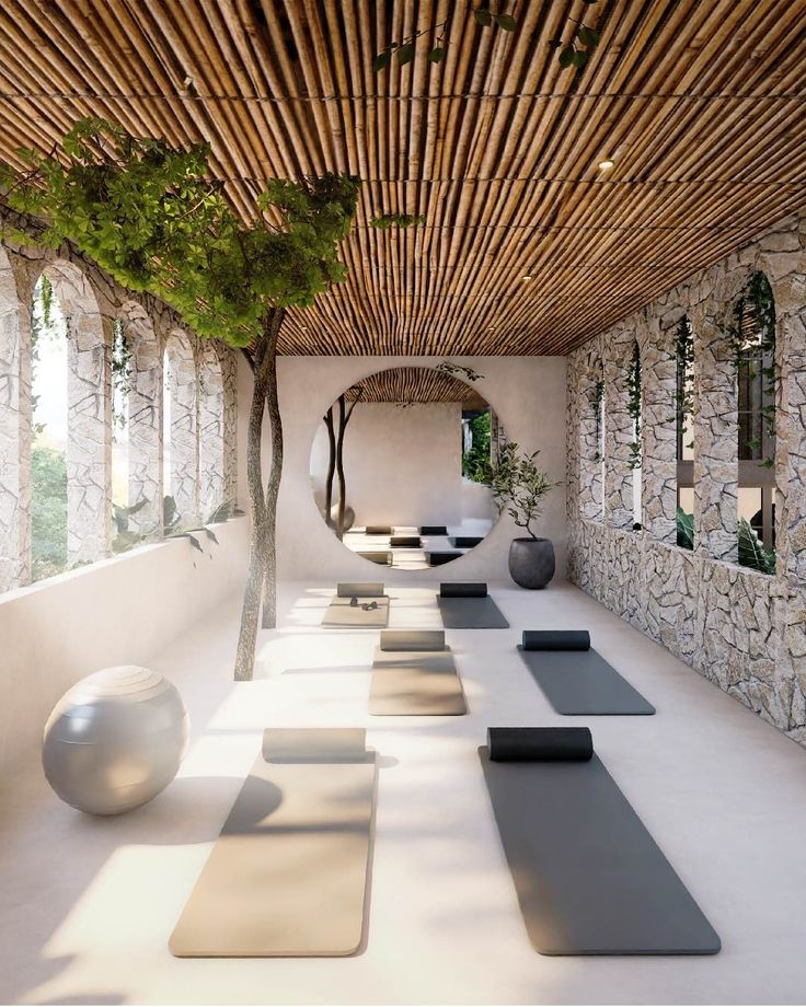 yoga mats lined up on the floor in a room with stone walls and bamboo ceilinging