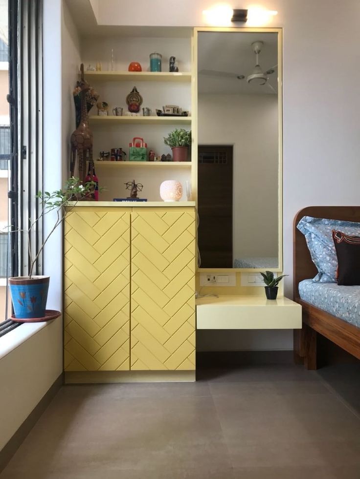 a living room with a couch, shelves and window in the corner next to it