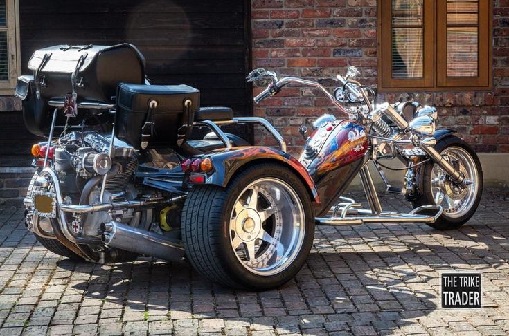 a motorcycle parked in front of a brick building with a trunk on it's back