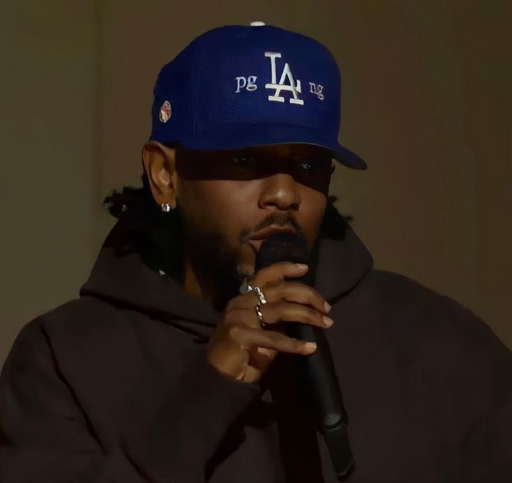 a man wearing a los angeles dodgers cap and holding a microphone