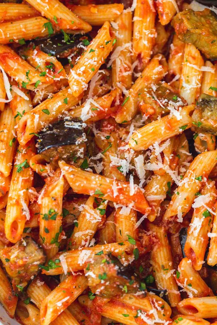 a bowl filled with pasta and sauce covered in parmesan cheese