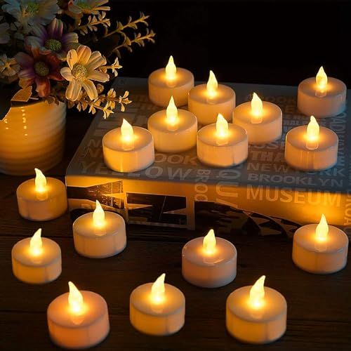 many lit candles are on a table next to a vase with flowers and a book