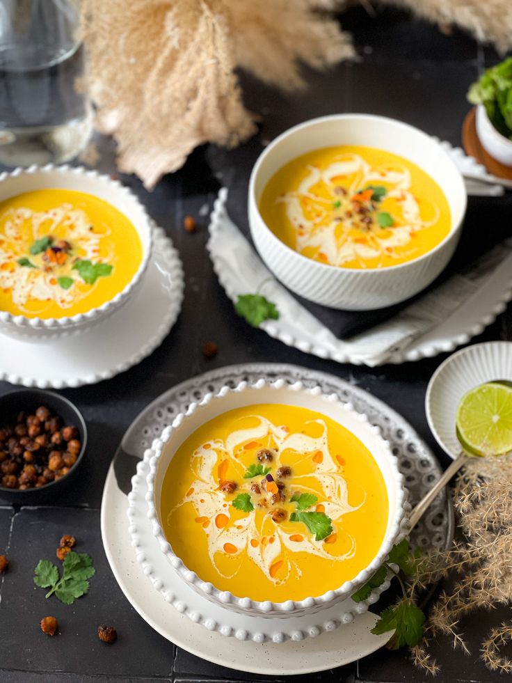 three bowls of soup with garnishes on the side