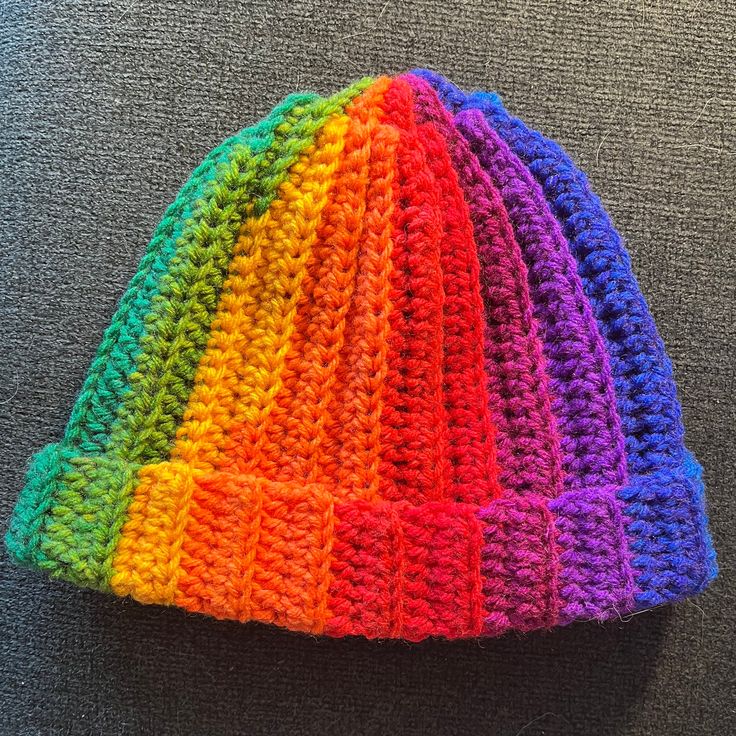 a multicolored crocheted hat sitting on top of a gray floor next to a wall