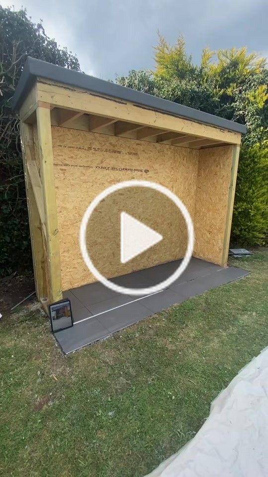 a wooden shed with the door open and a play button on it's side