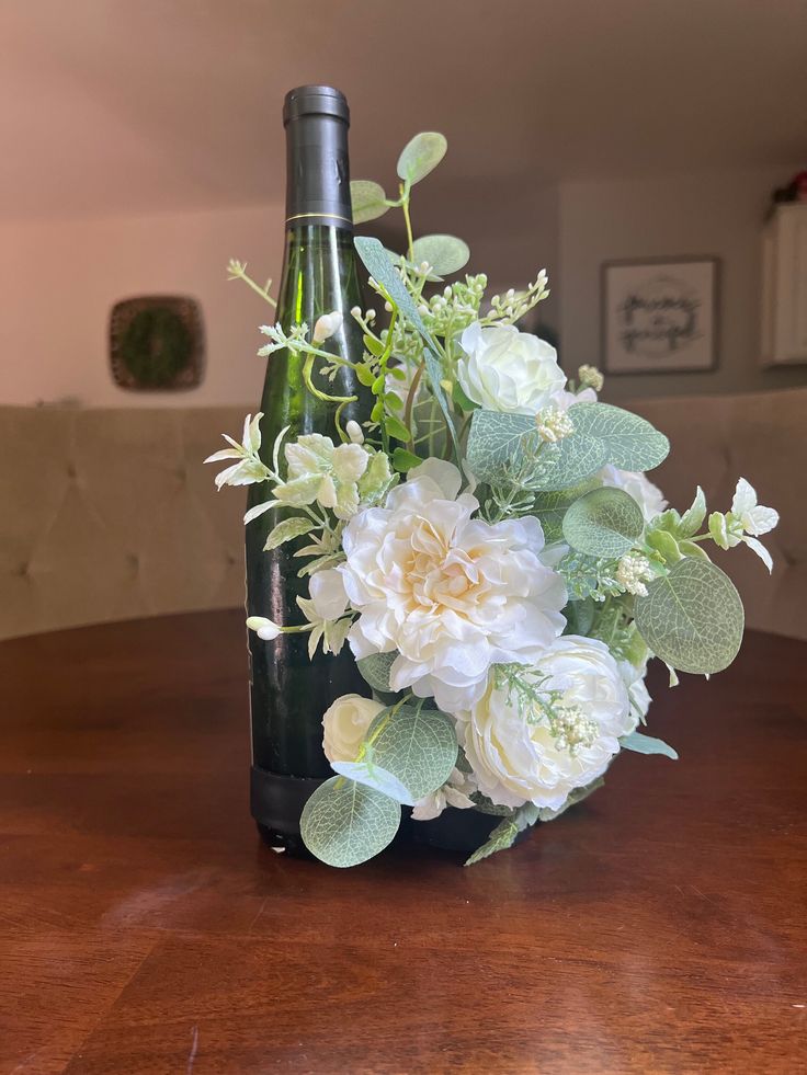 a vase filled with flowers sitting on top of a table next to a wine bottle