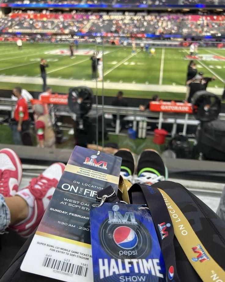 someone is sitting in the bleachers at a football game with their luggage and tickets