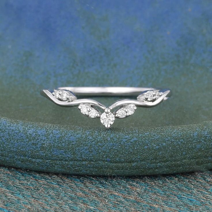 a white gold wedding band with three diamonds on the top and two leaves at the bottom