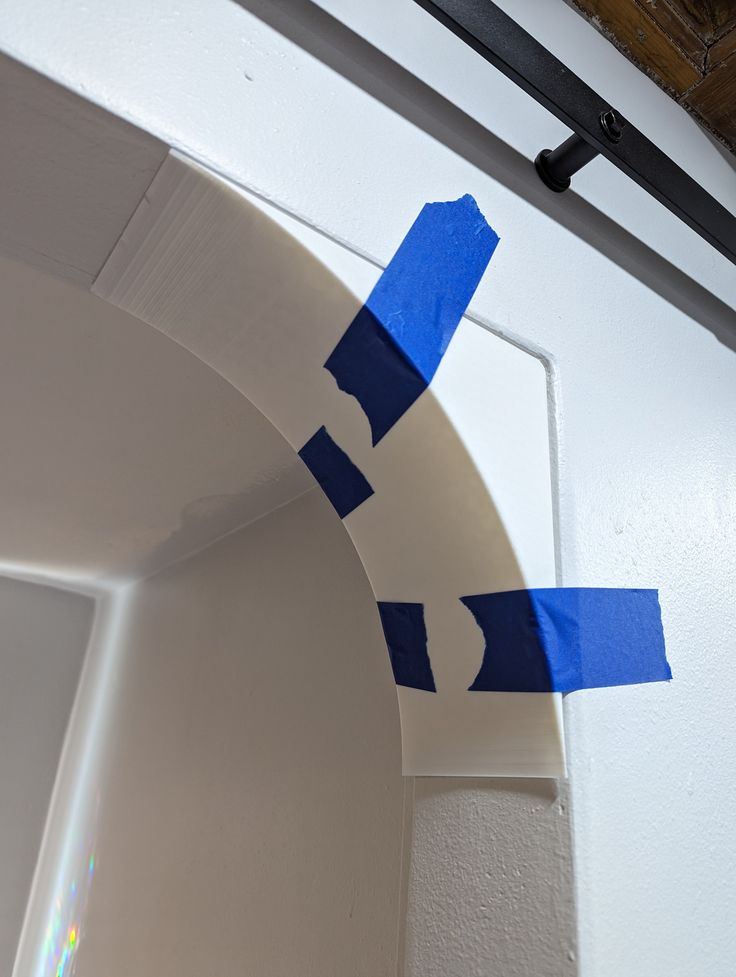 blue tape is taped to the side of a white door with an arch in it