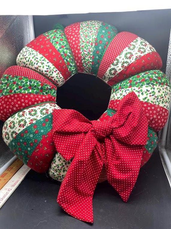 a red and green wreath sitting on top of a window sill