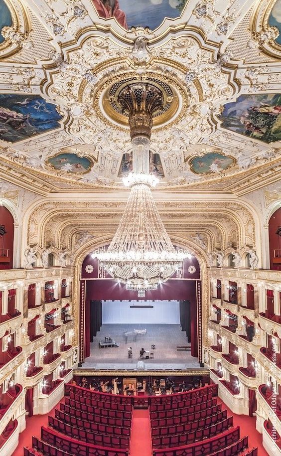 an empty auditorium with red seats and painted ceilings