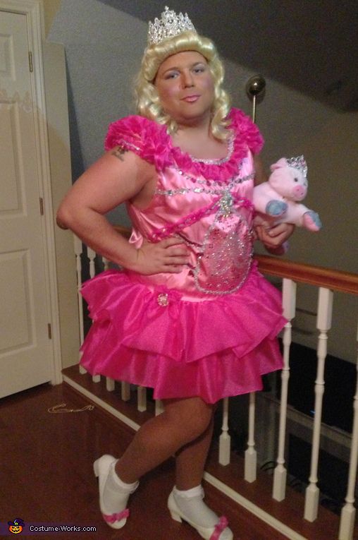 a woman in a pink dress and tiara holding a stuffed animal while standing on a stair case