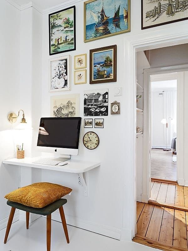 there is a desk with a computer on it and many pictures around the wall behind it