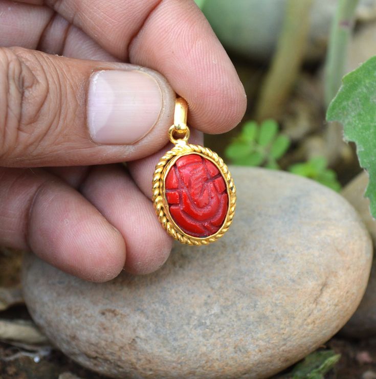 a person is holding a red pendant in their hand