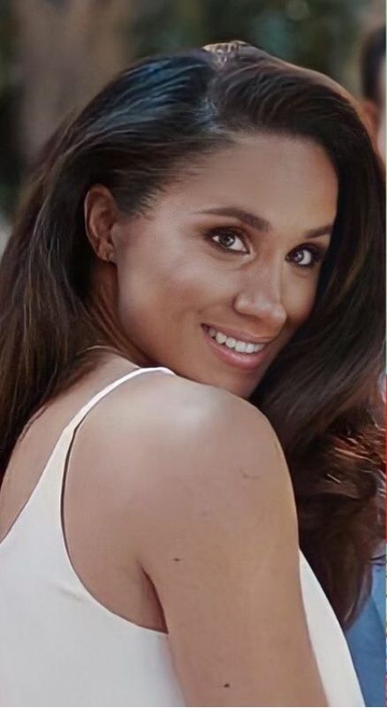 a woman with long dark hair smiling and wearing a white tank top on the street