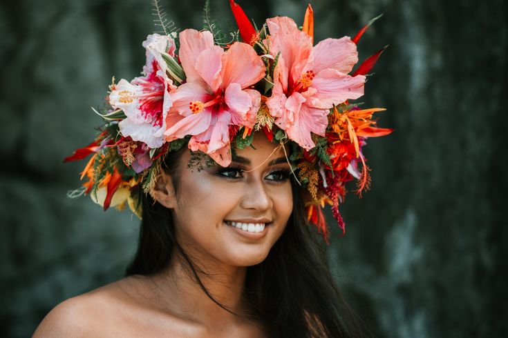 a woman with flowers in her hair smiling at the camera while wearing a flower crown