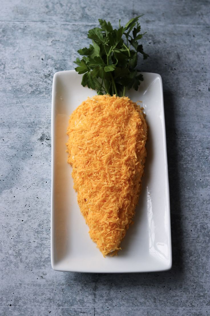 a piece of food that is on a white plate next to a leafy plant