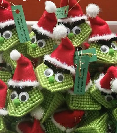 green and red knitted christmas ornaments with santa hats on them for sale in a store