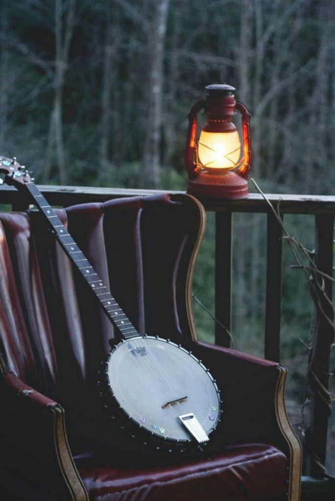 a guitar sitting on top of a chair next to a lamp