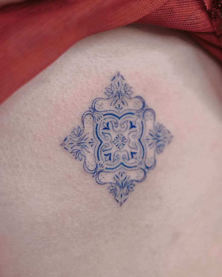 a blue and white tattoo on the back of a woman's stomach