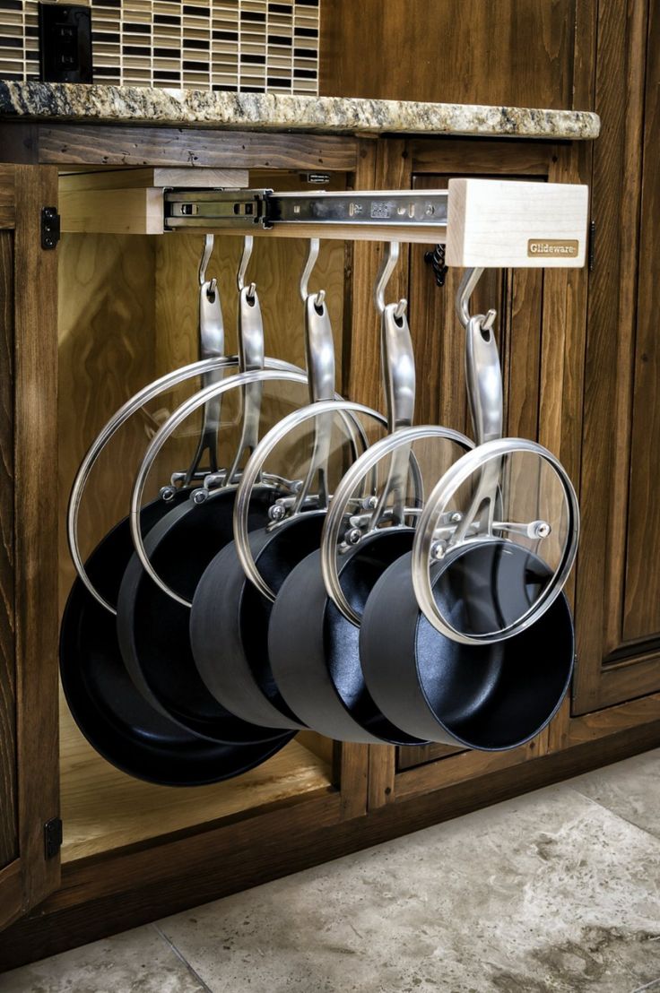 pots and pans are hanging on the rack in this kitchen cabinet with marble countertops