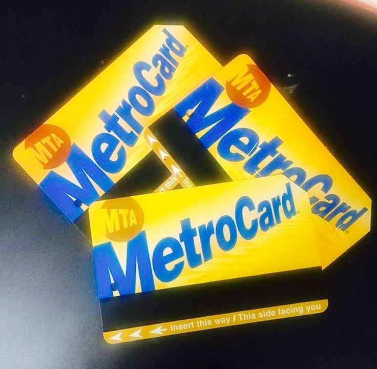 two metro card stickers sitting on top of a black surface with yellow and blue lettering