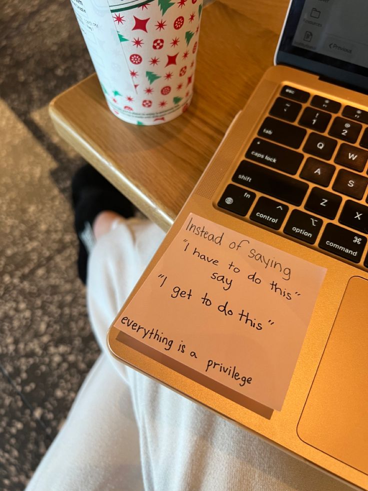 an open laptop computer sitting on top of a wooden table next to a cup of coffee