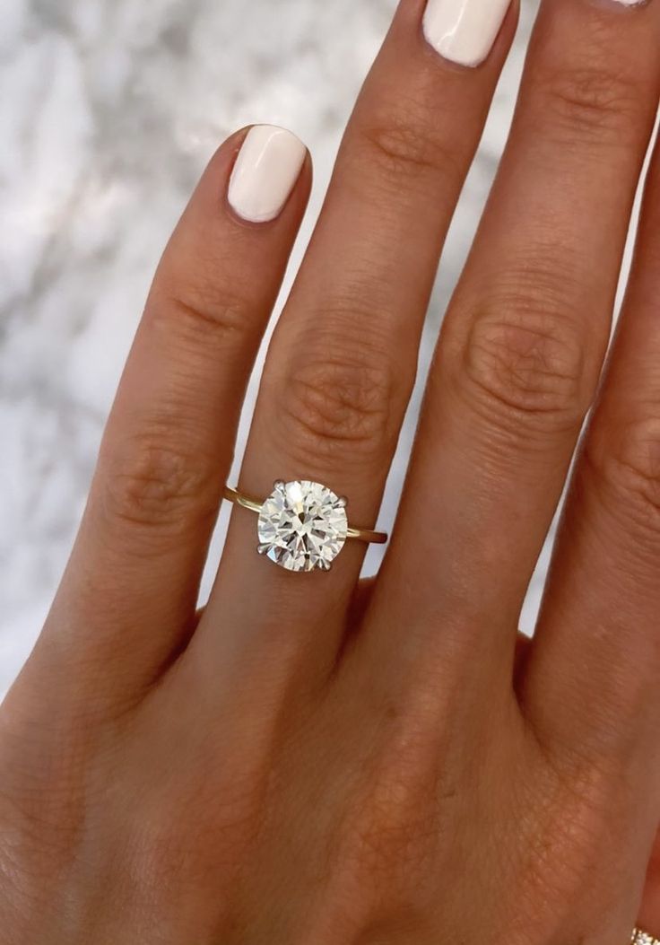 a woman's hand with a white manicured nail polish and an engagement ring