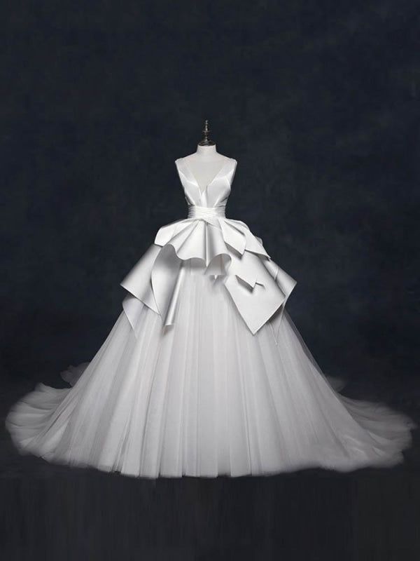 a white wedding dress on display in front of a dark background with the back bow down