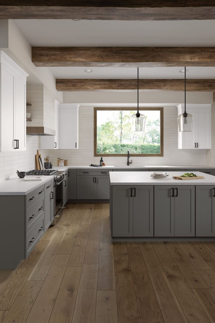 a large kitchen with wooden floors and gray cabinets, along with white counter tops on both sides