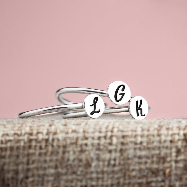 Wrap your fingers in the timeless elegance and personal charm of our Set of 3 Signet Initial Stacking Rings. Imagine carrying the your loved ones' initials right at your fingertips - a gentle reminder of life's blessings and the love that surrounds you. Each delicately engraved round disc can be personalized with an initial, forging a bond with those who fill your heart with joy - be it children, a spouse, or someone dear. These rings are a beautiful representation of motherhood or a symbol of t Minimalist Engraved Ring With Initials For Anniversary, Minimalist Stackable Rings With Initials For Anniversary, Minimalist Initials Rings For Anniversary, Minimalist Jewelry With Initials For Anniversary, Minimalist Anniversary Rings With Initials, Minimalist Stackable Wedding Rings With Initials, Adjustable Initial Name Ring, Minimalist Engraved Ring With Initials For Promise, Initials Engraved White Gold Ring