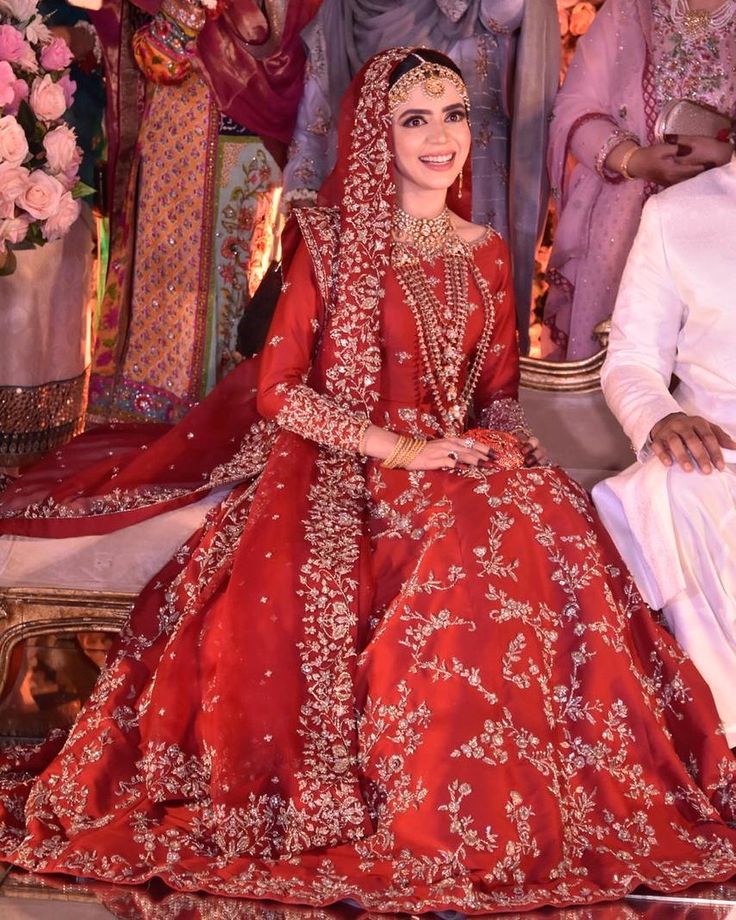 the bride and groom are posing for a photo in their red wedding gowns,