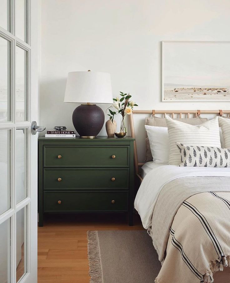 a bedroom with white walls and green dresser next to the bed in front of it