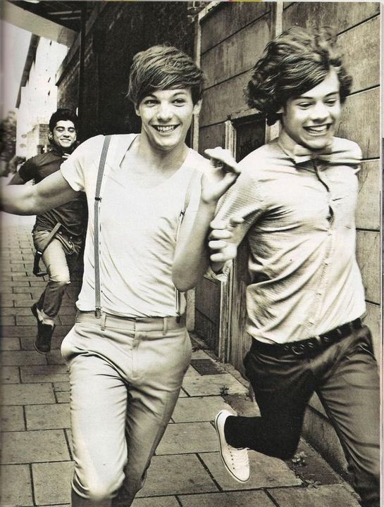 two young men are running down the street in suspenders and bow ties, one is smiling at the camera